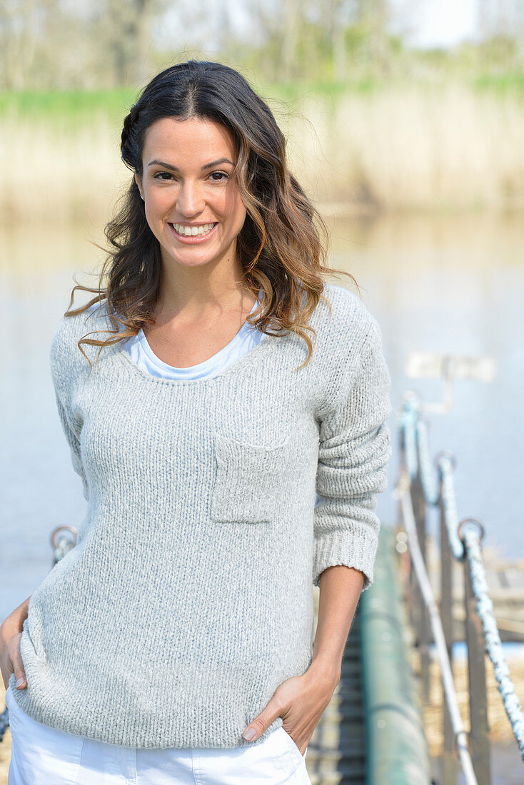 A young woman wearing a grey jumper near river