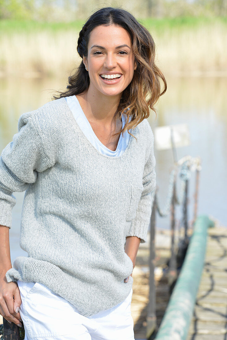 A young woman wearing a grey jumper and white shorts near river