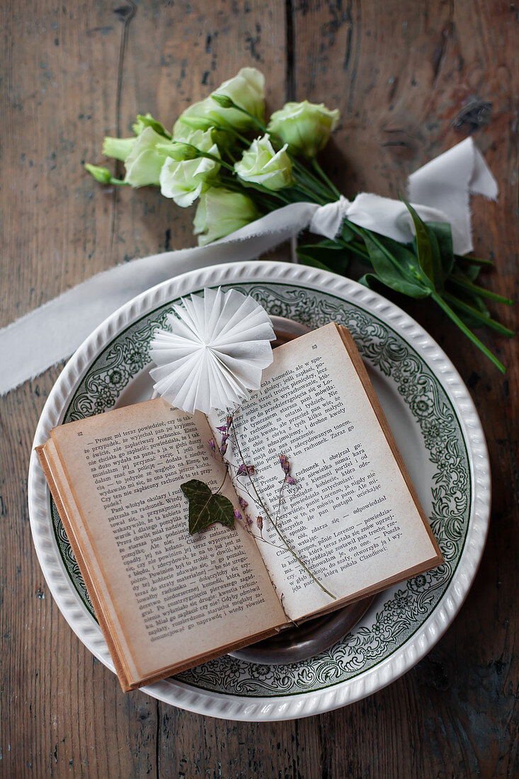Ivy leaf and paper rosette on open book