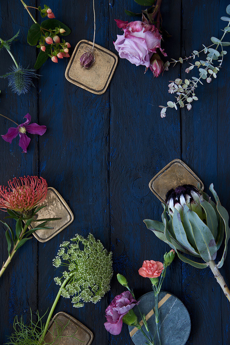 Roses, pinks, eucalyptus, clematis, proteas, Banksia, St. John's wort, sea holly and wild carrot on blue surface