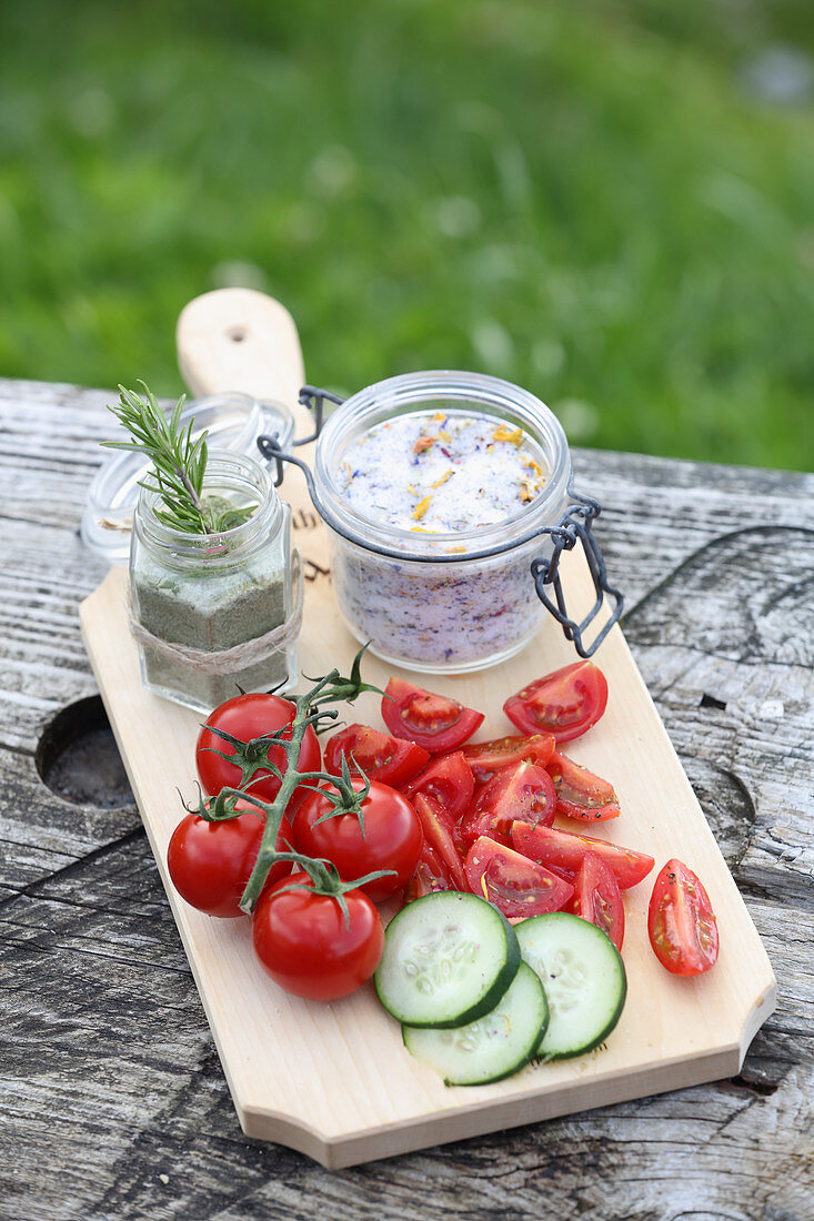 Tomatoes and cucumber with homemade herb salt on a wooden board