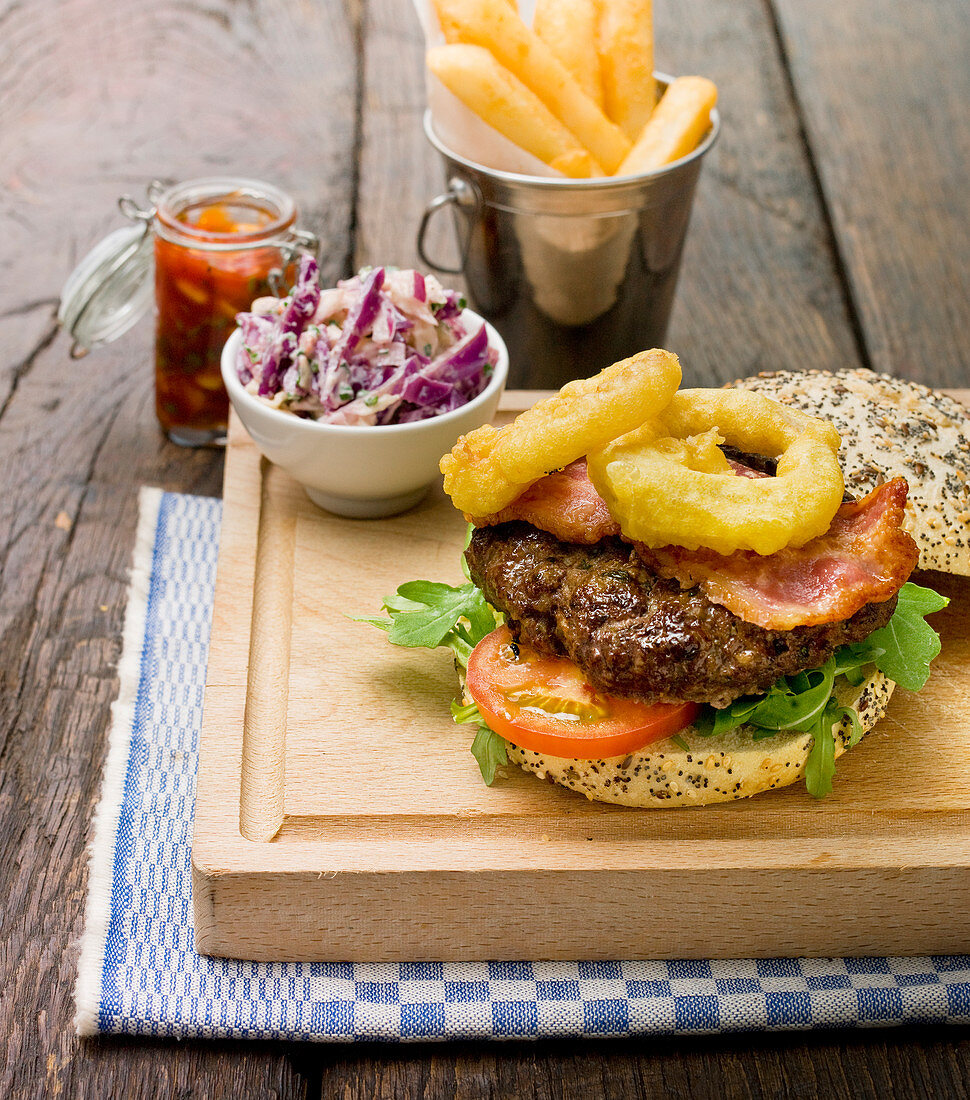 Hausgemachter Burger mit Rucola, Tomate, Bacon und Zwiebelringen