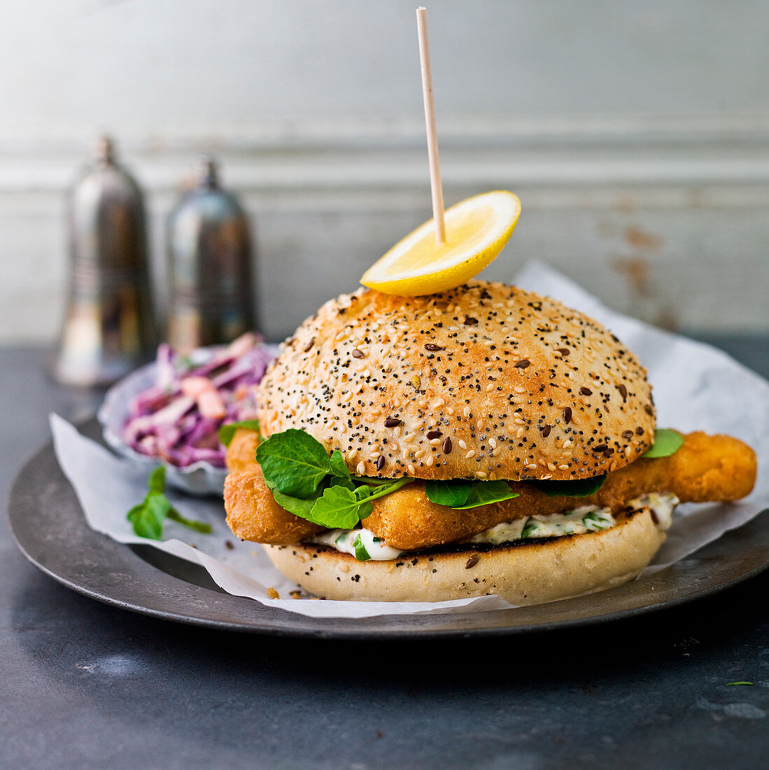 Fish fingers in a seeded roll, with lettuce, coleslaw, lemon wedge