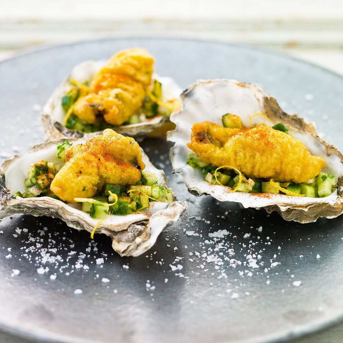 Battered Oysters on a bed of cucmber salad, served in oyster shells with a sprinkling of chilli powder, lemon zest and rock salt