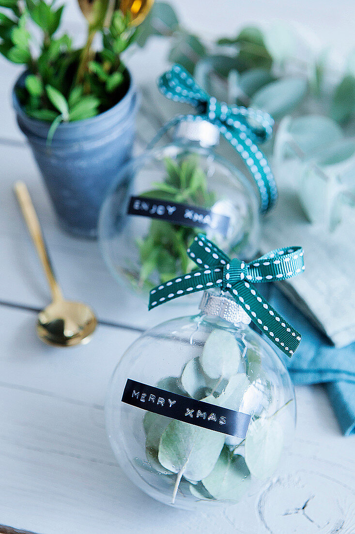 Glass baubles filled with leaves and labelled with Christmas greetings