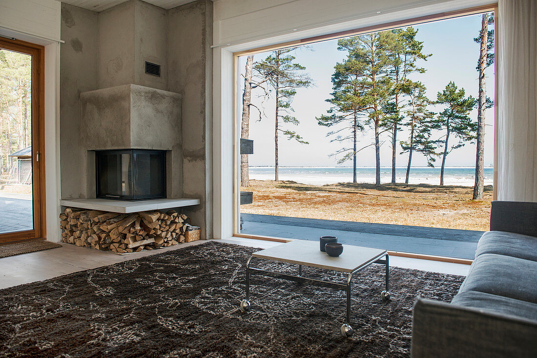 Wohnzimmer mit Eckkamin und Panoramafenster mit Blick aufs Meer