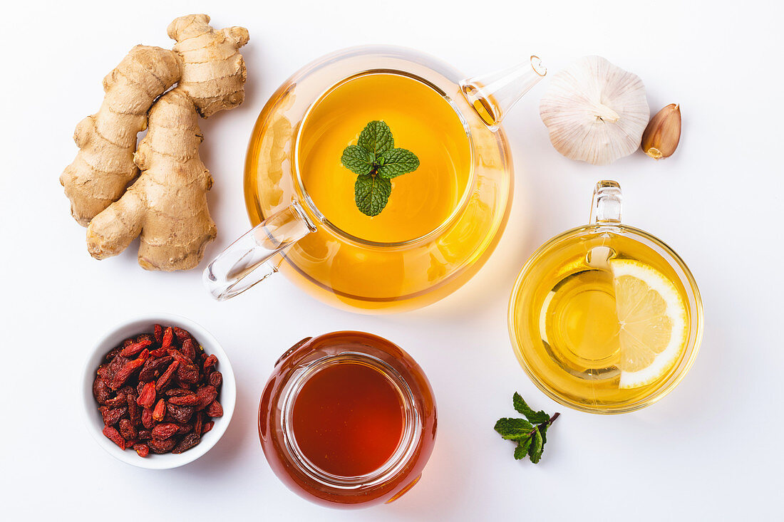 Homemade ginger and lemon tea, honey, goji, garlic, white background