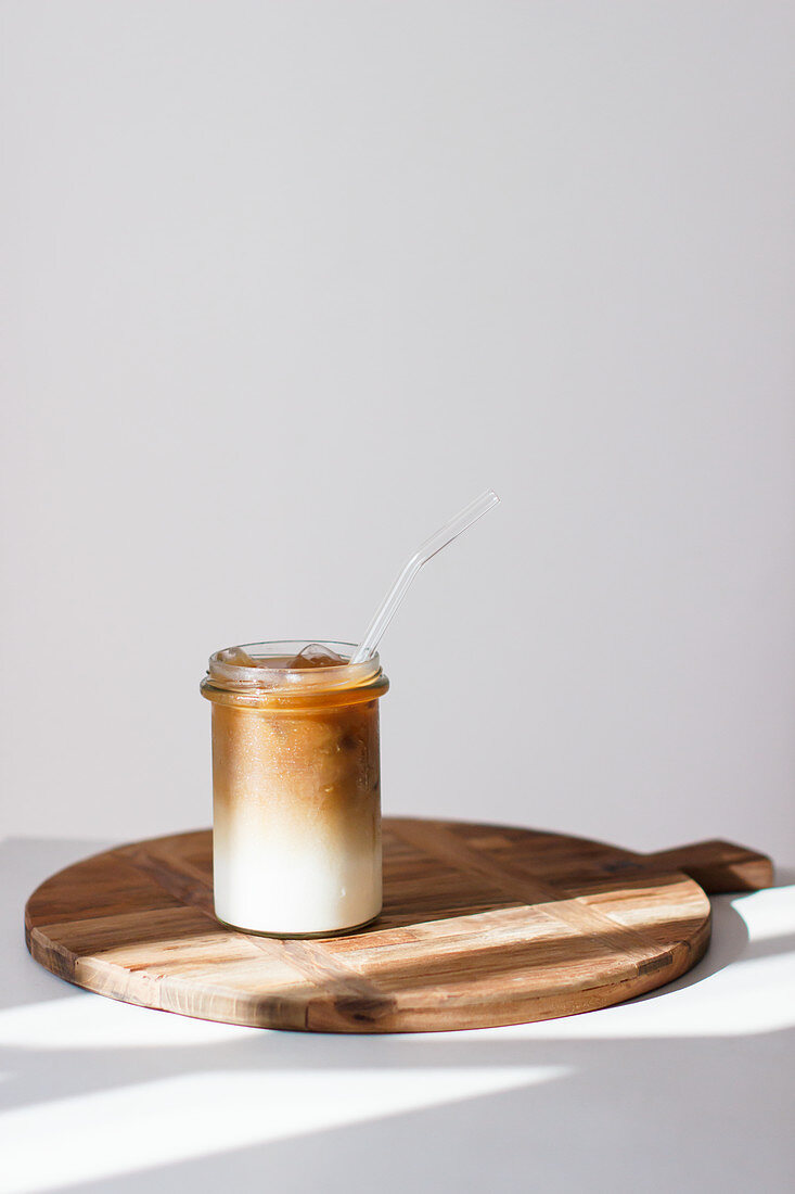 Iced Coffee auf Holzbrett vor weißem Hintergrund