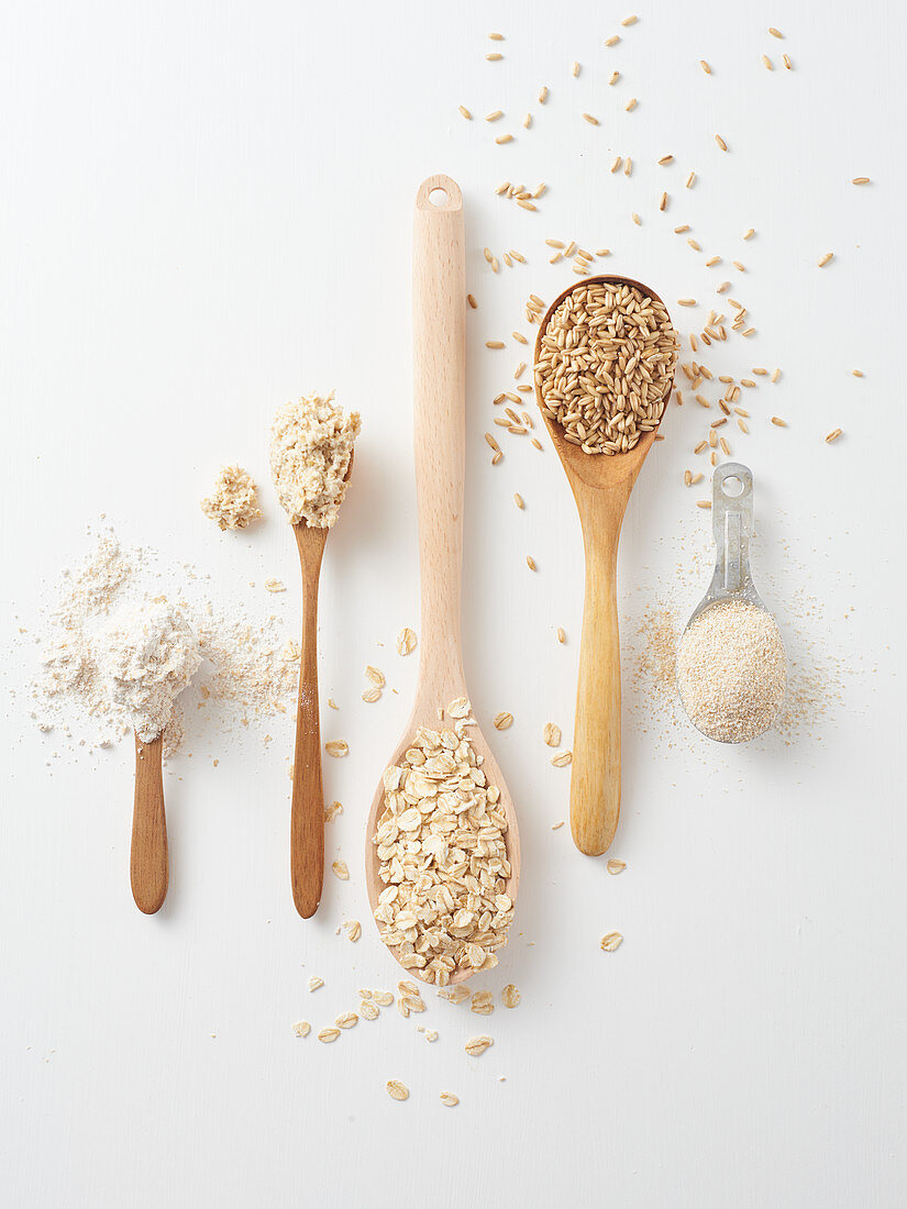 Oat grains, oat flakes, porridge and oatmeal on spoons