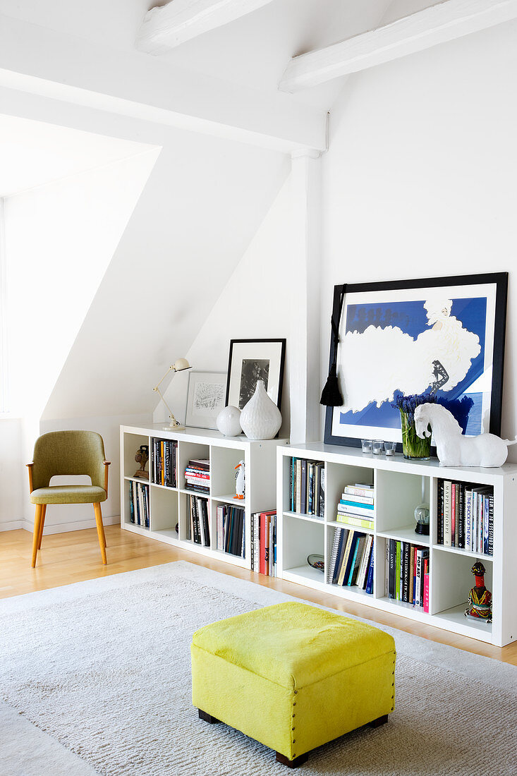 Yellow ottoman next to white shelves in living room