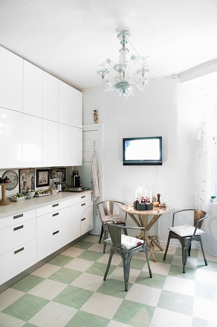 Metal chairs around table in kitchen with green-and-white chequered floor