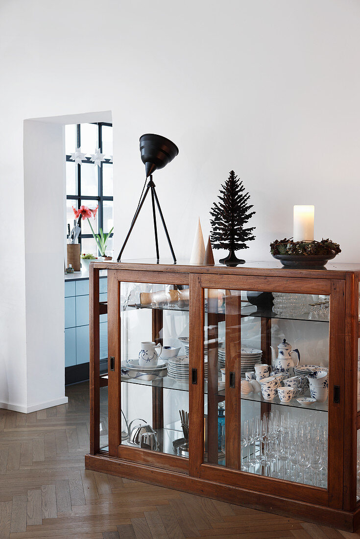 Glasses and crockery in old display case with Christmas decorations on top