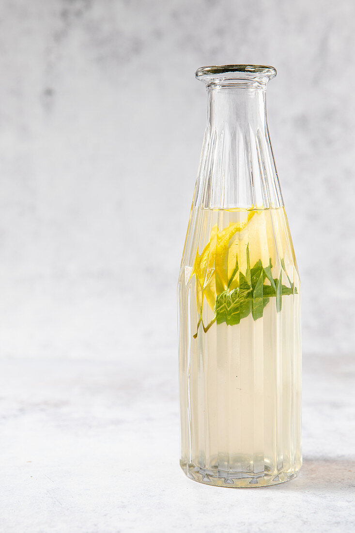 Kalter Pfefferminztee mit Zitrone in Glasflasche