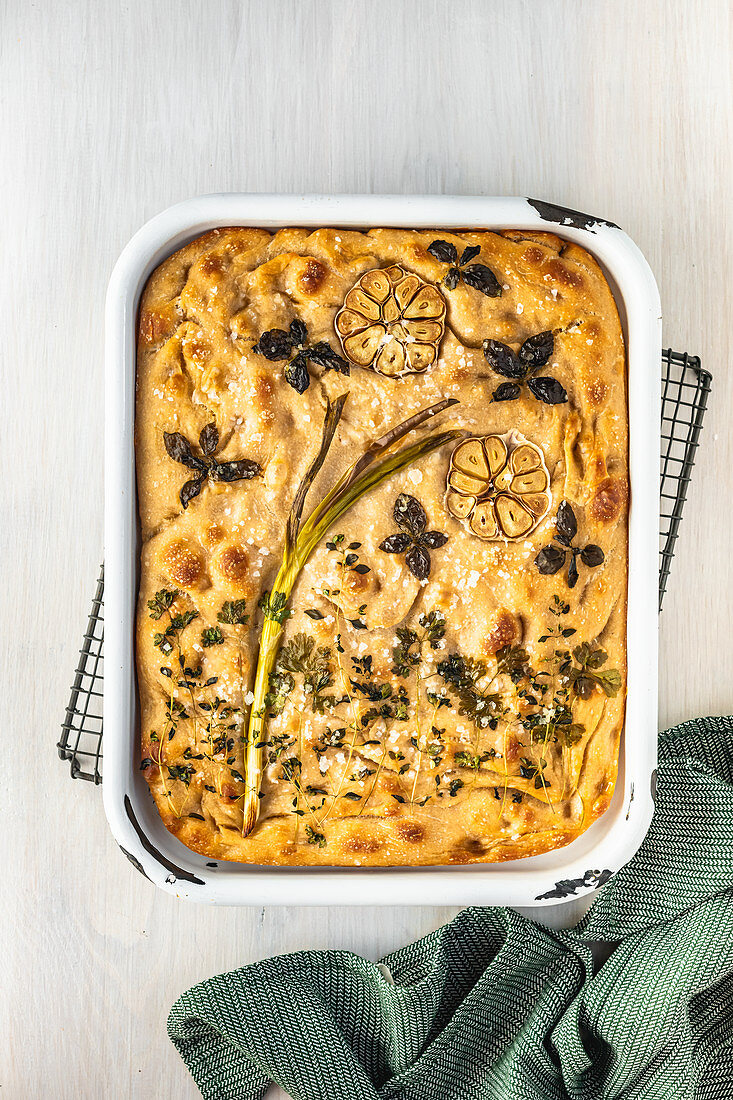 Sourdough focaccia with a flower picture made of herbs, spring onions and garlic