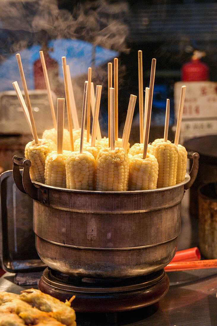 Gekochte Maiskolben auf Holzspiessen (Street Food in Peking)