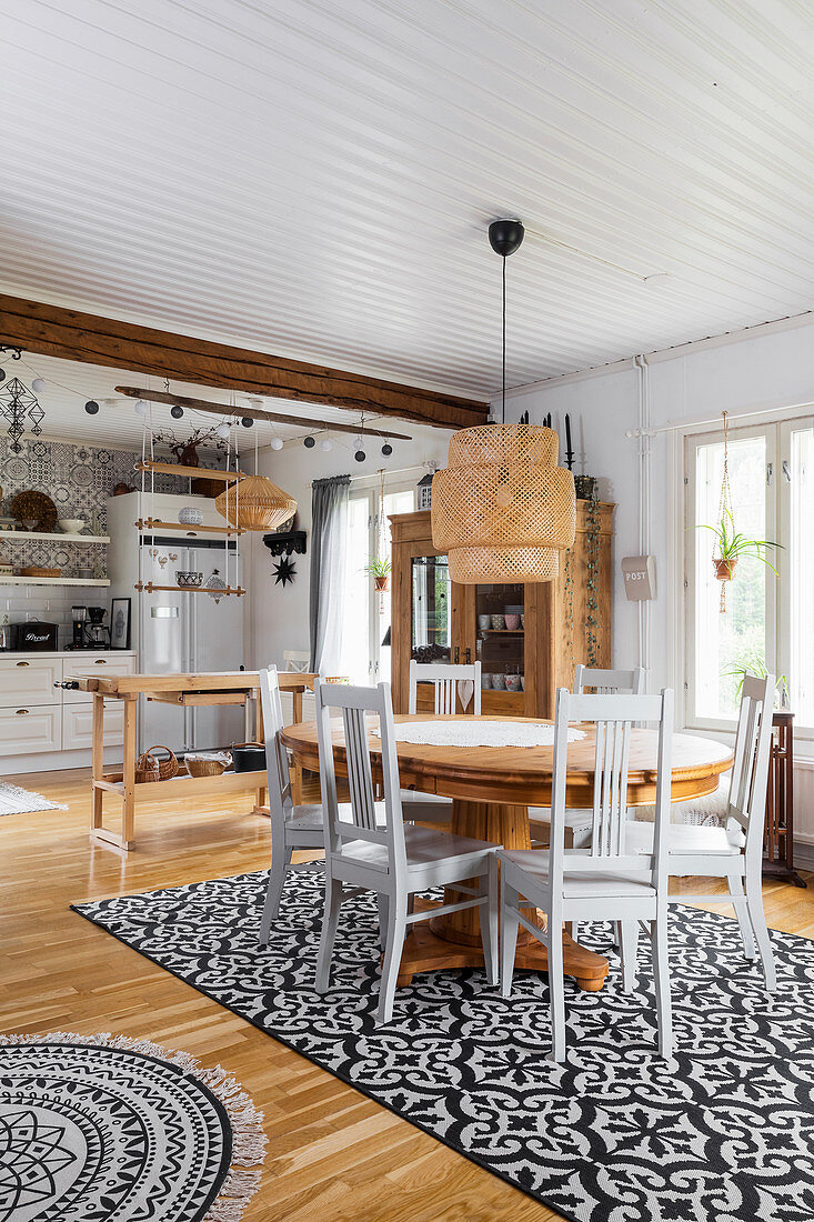 Dining table and country-house kitchen in open-plan interior in Bohemian style