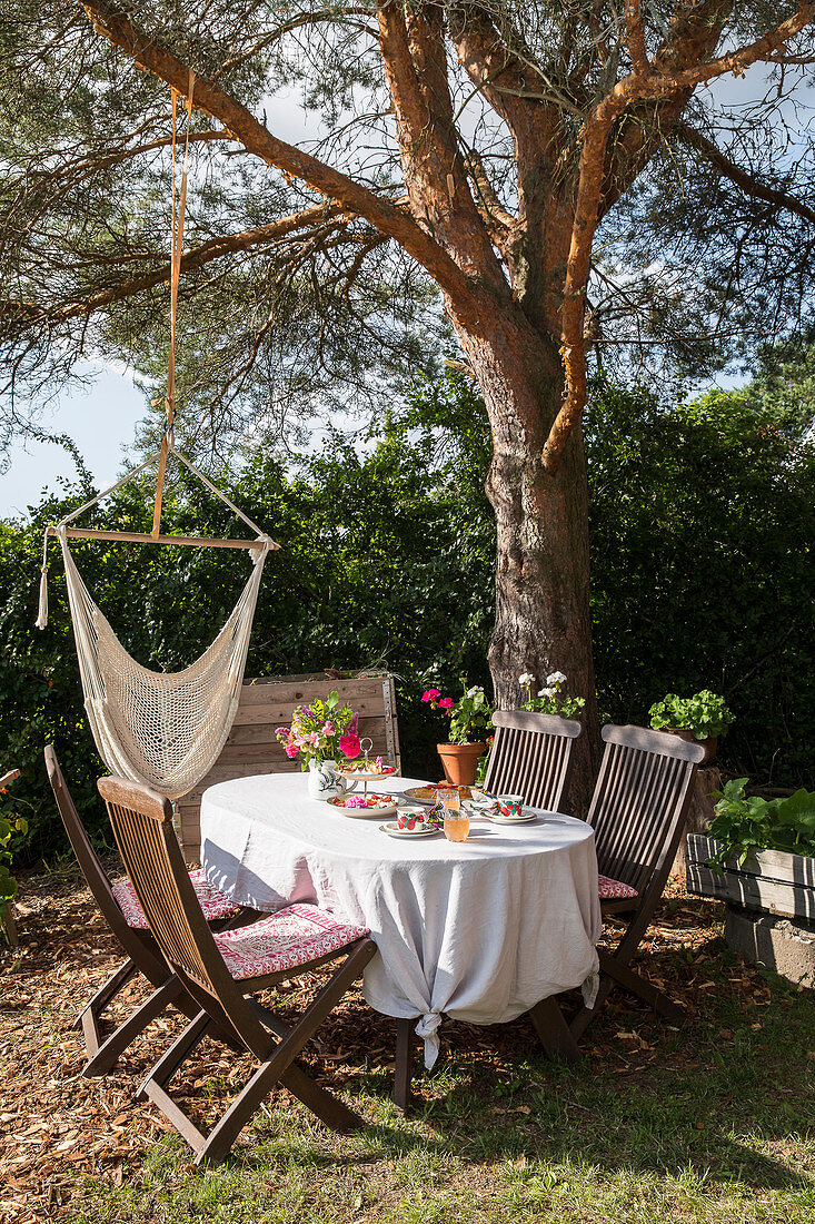 Set table with knotted tablecloth in summery garden