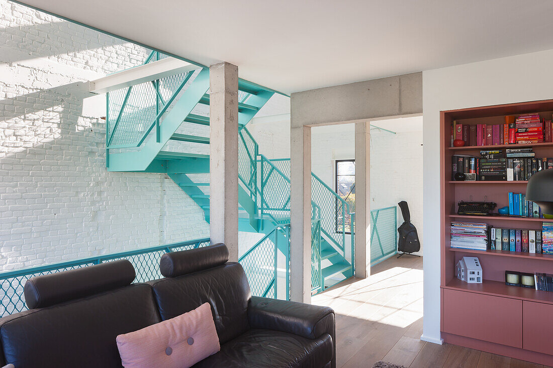 Living room with black leather sofa and turquoise-colored spiral staircase