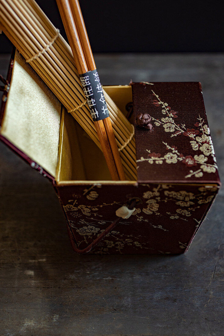 An oriental silk box with a bamboo mat and chopsticks