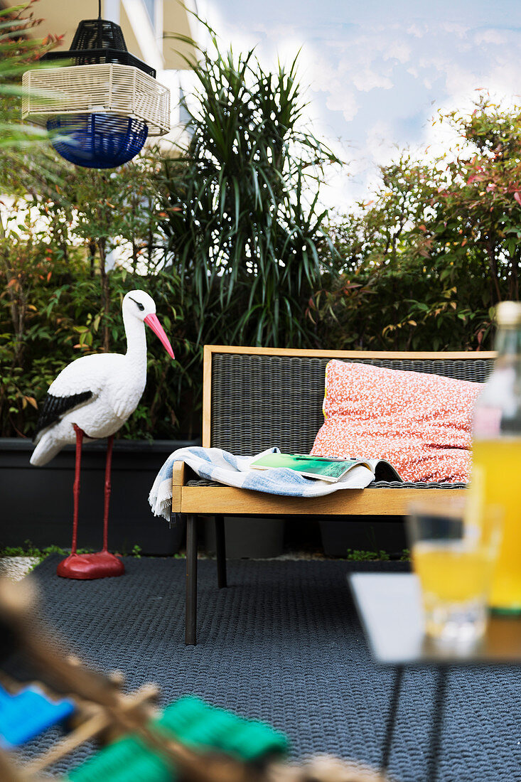 Stork ornament on balcony screened by plants