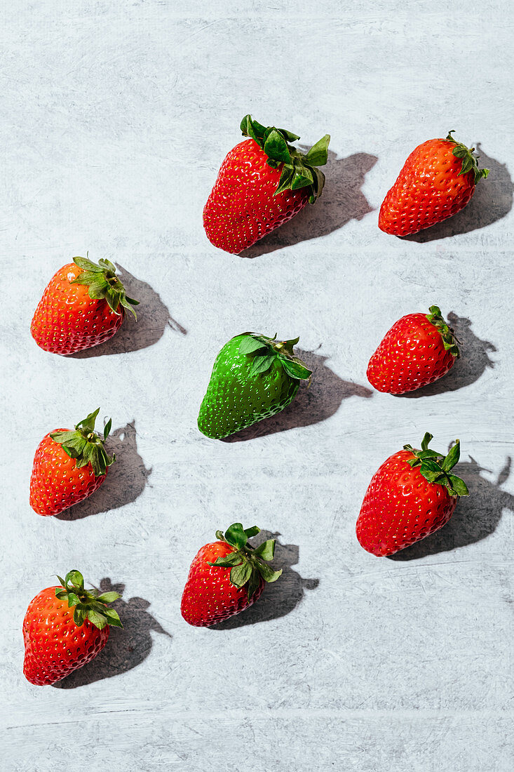 Fresh ripe red and green strawberries placed in gray table