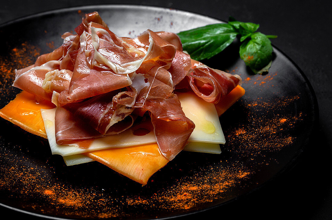 Homemade toasted bread with ham and different types of cheeses on dark background