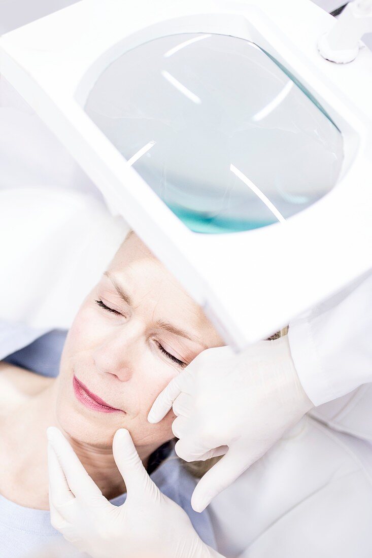 Beauty technician examining woman's skin