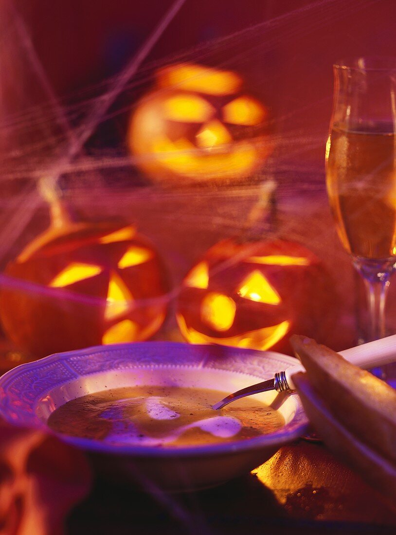Pumpkin cream soup with sour cream, decor; illuminated pumpkins