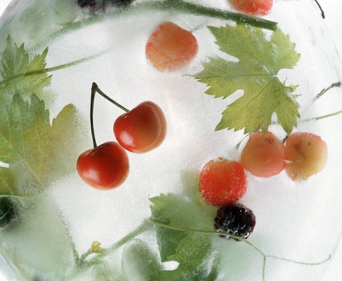 Cherries and vine leaves frozen in ice