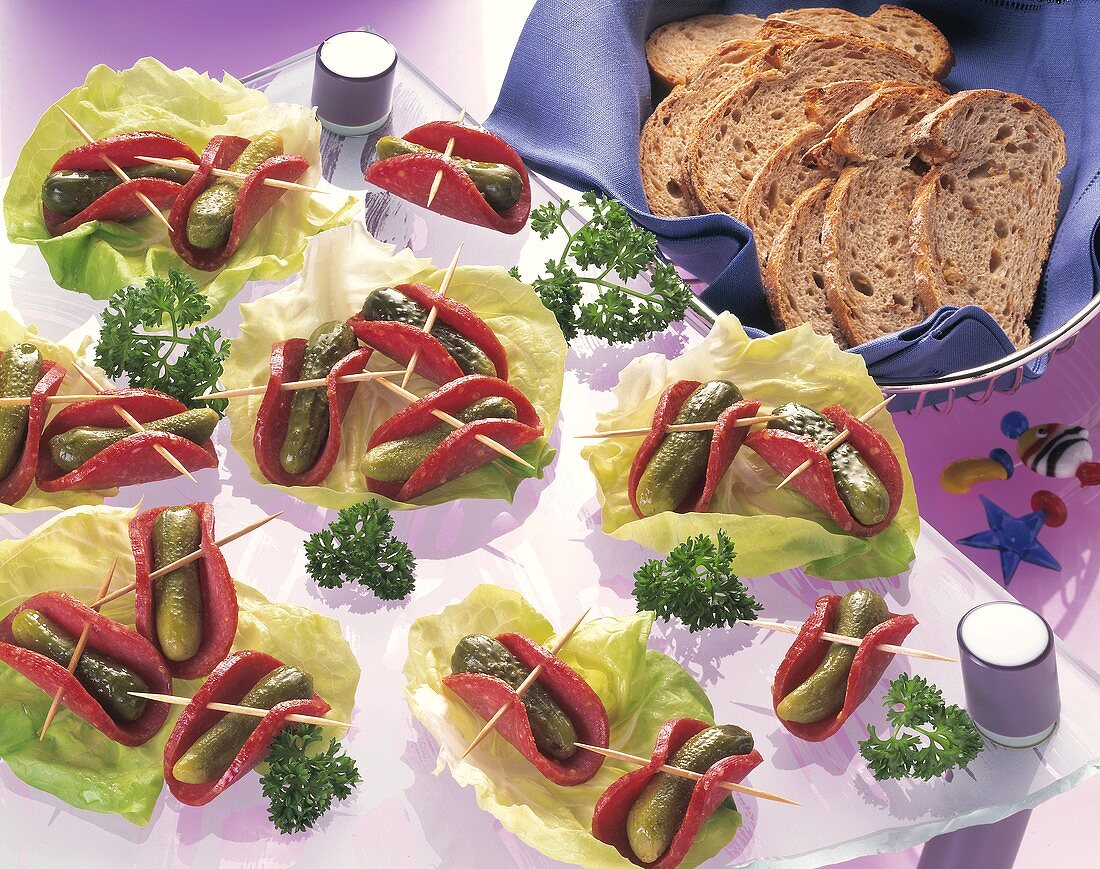 Salami-Gurken-Häppchen auf Salatblättern & Brot im Brotkorb