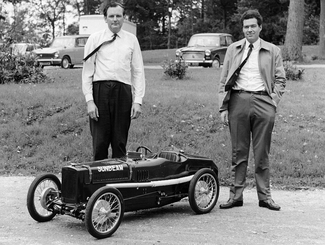 Two men standing by a miniature Sunbeam pedal car, 1960s