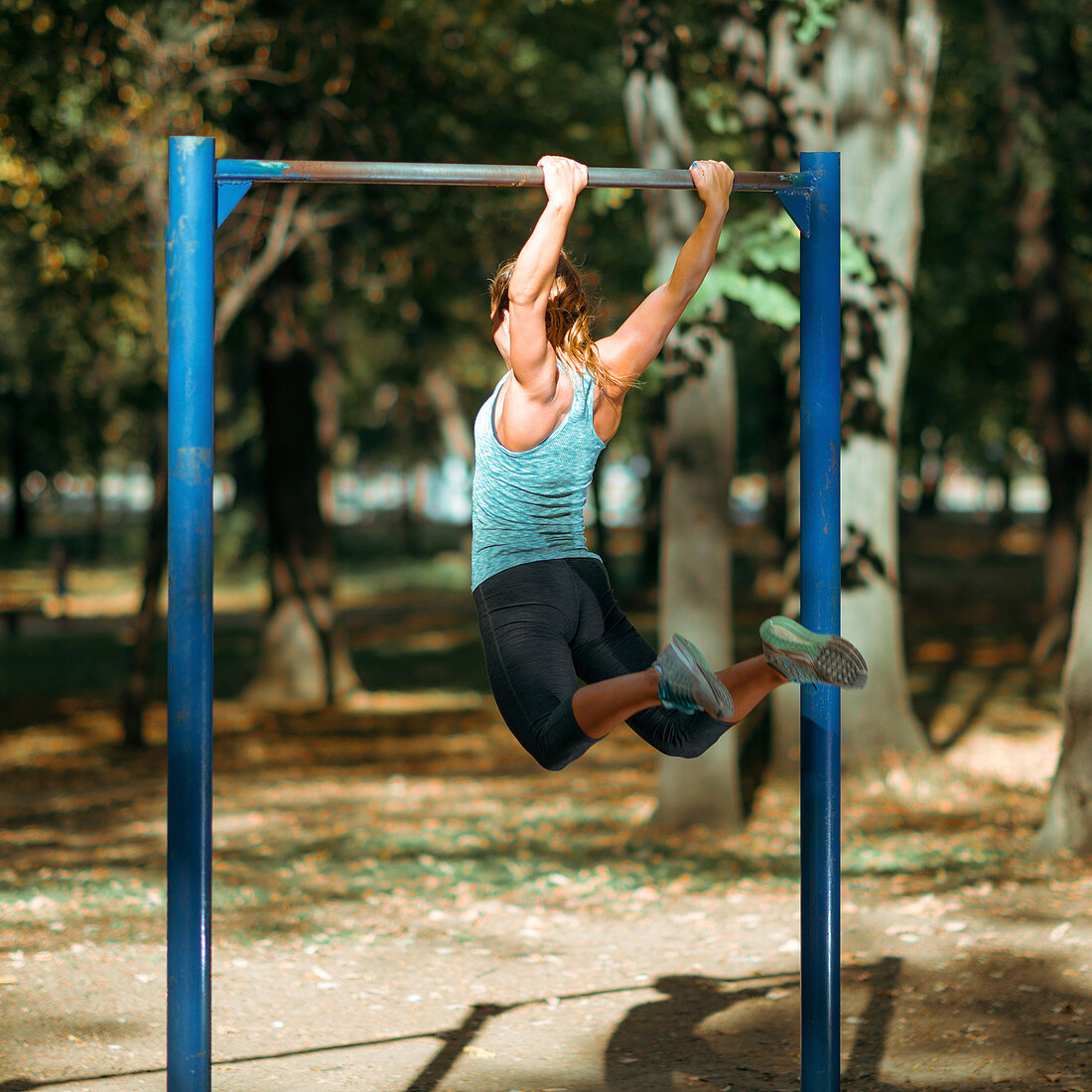 Woman exercising on outdoor horizontal bar