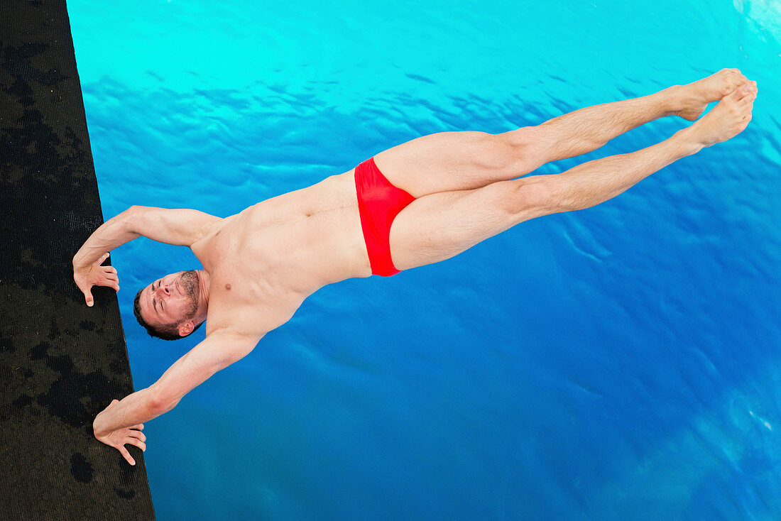Male diver in handstand on diving platform