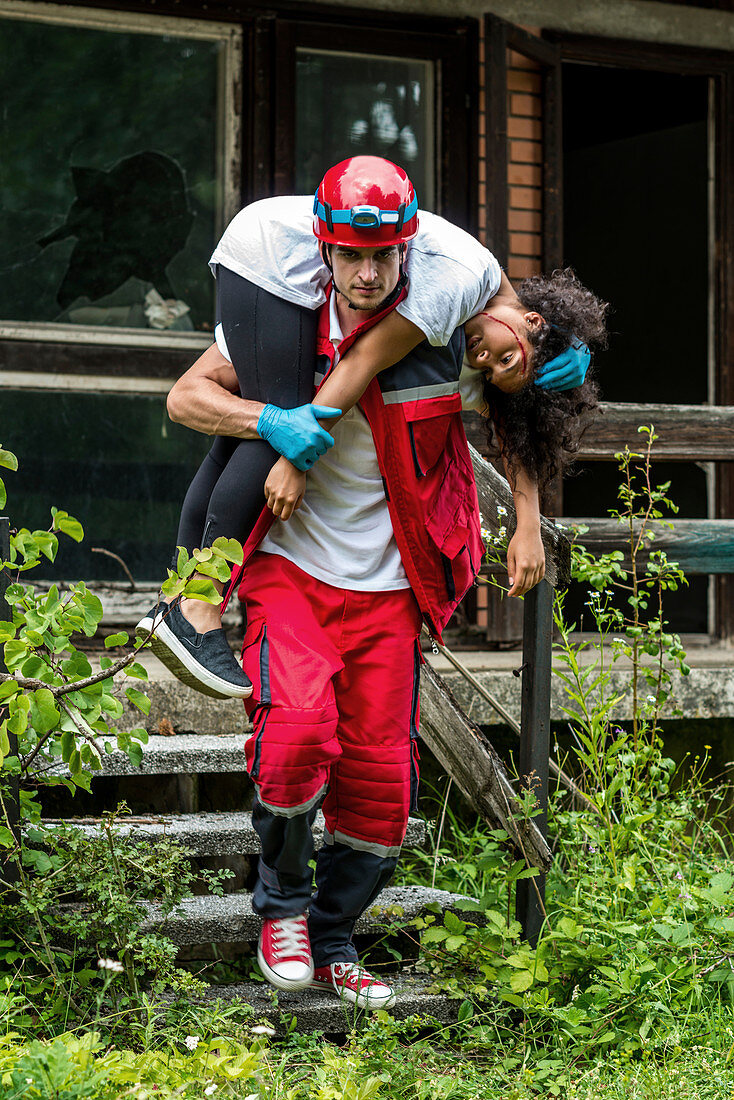 Rescue worker evacuating woman from house