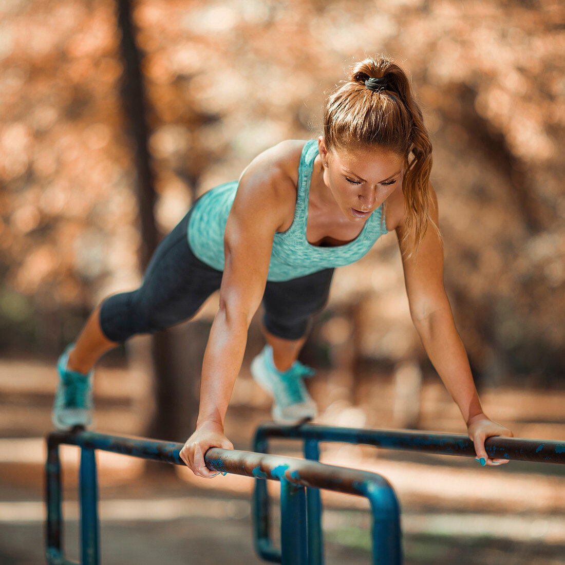 Woman exercising on parallel bars outdoors