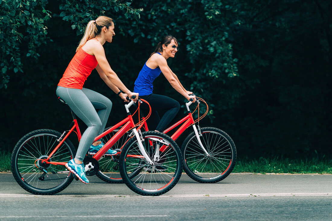 Women riding bikes together in a park