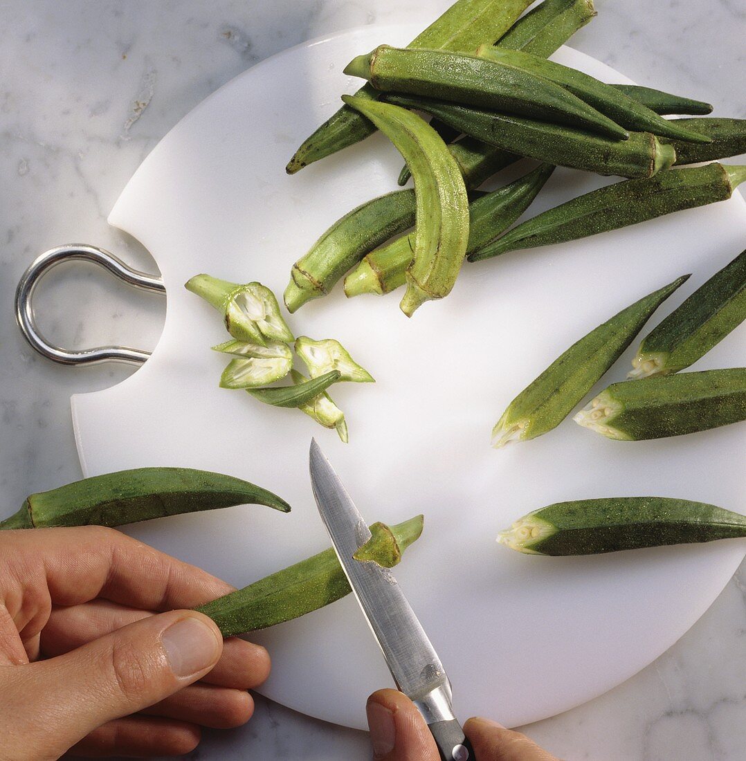 Preparing okra pods and cutting the stalk to a point