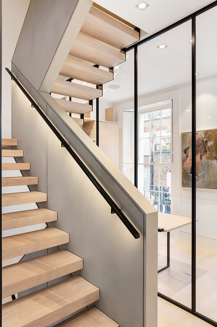 Indirect lighting below handrail of staircase with open treads