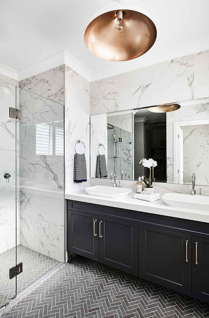 Washstand in elegant bathroom with marble tiles and shower area