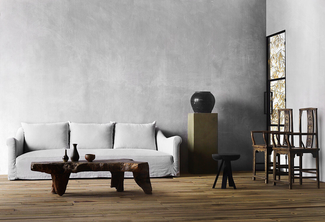 Solid coffee table, upholstered sofa, stele with vase and two chairs in the living room with gray walls