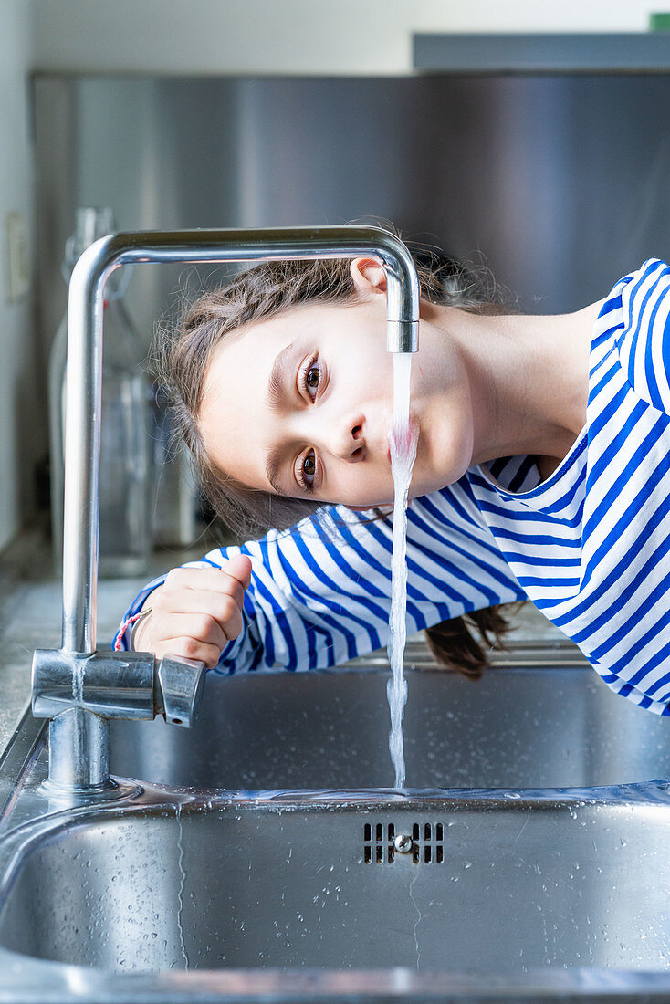 Young girl drinking tap water