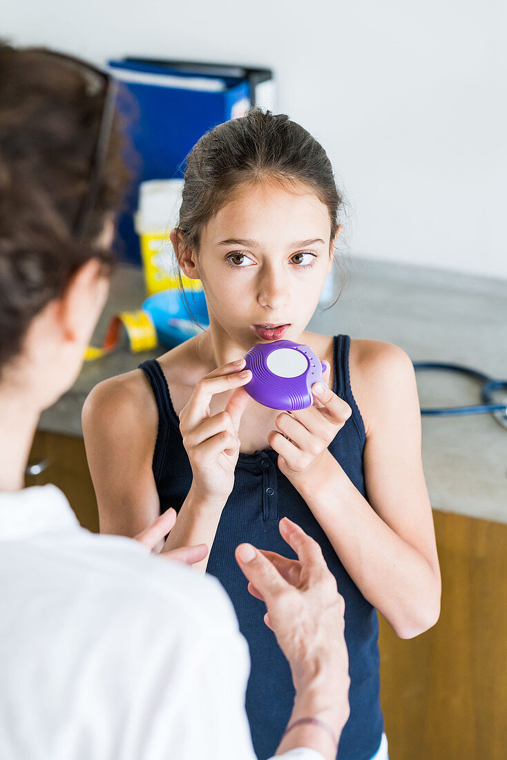Doctor instructing a girl on how to use asthma inhaler