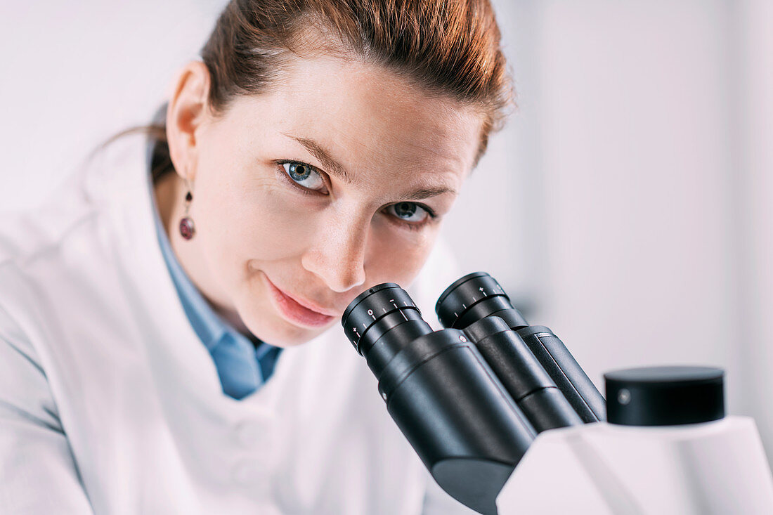 Portrait of young female archaeologist with microscope