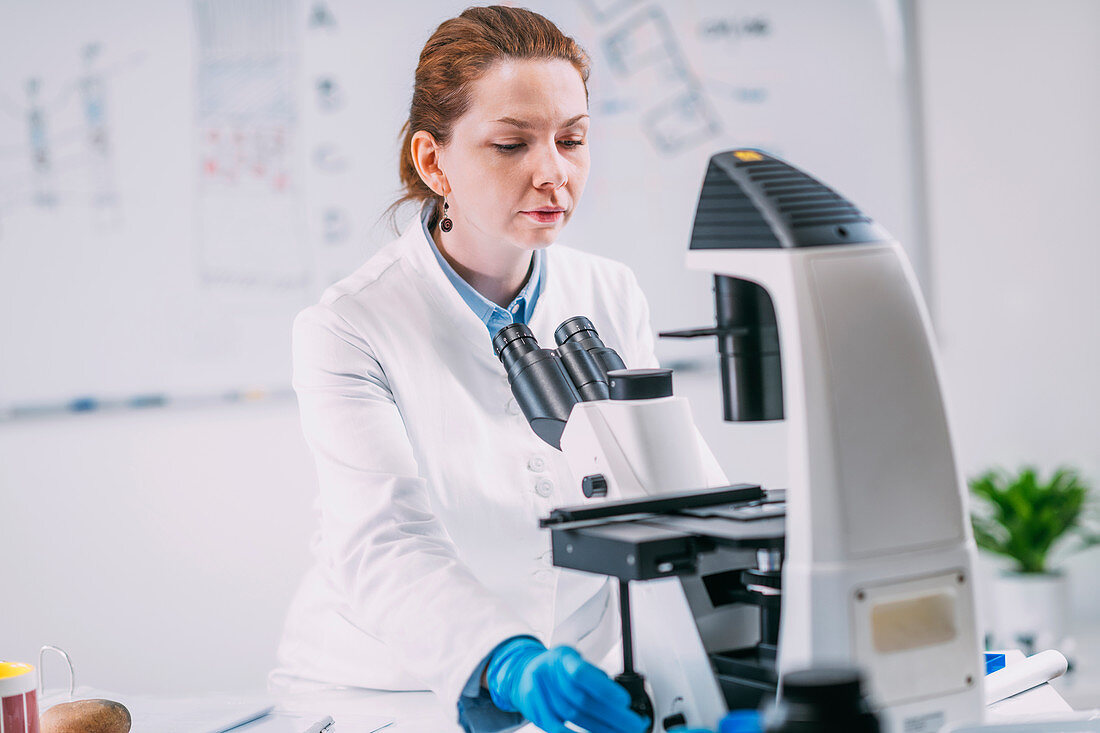 Portrait of young female archaeologist with microscope