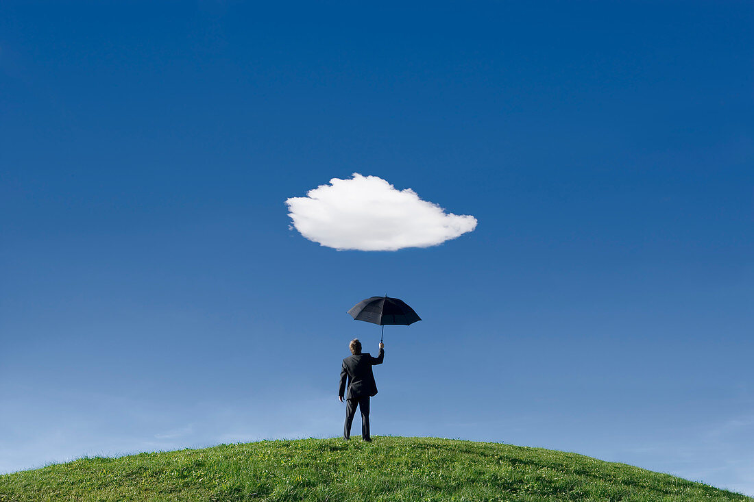 Businessman holding umbrella underneath a single cloud
