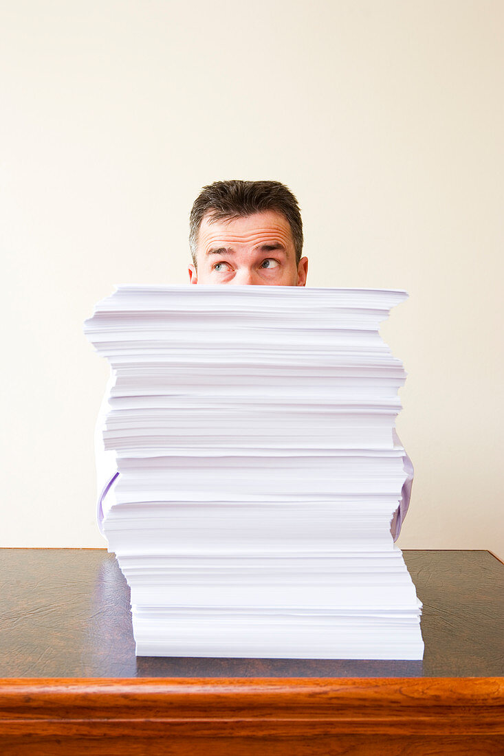 Businessman behind stack of papers