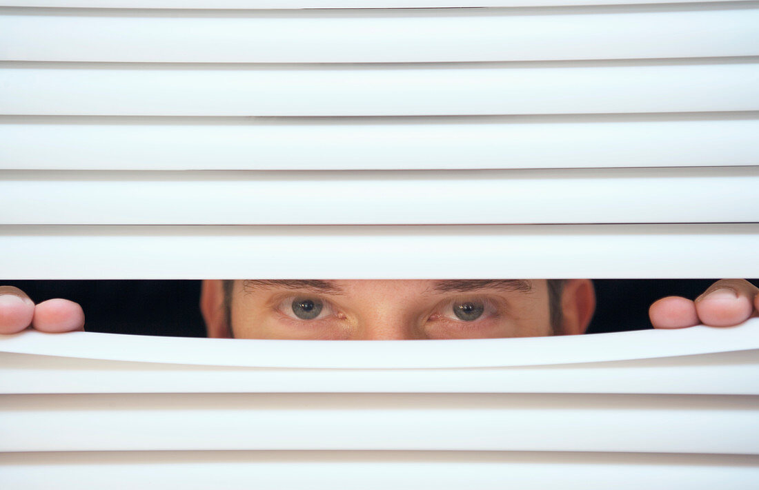 Man peeking through venetian blinds