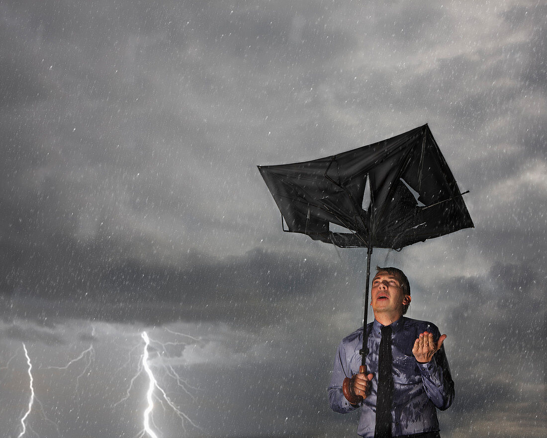 Businessman with broken umbrella in a storm