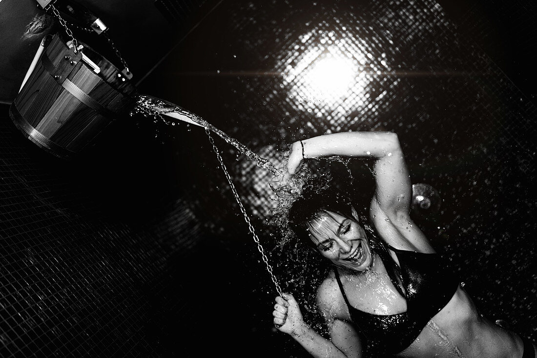 Woman taking a cold shower from ice bucket
