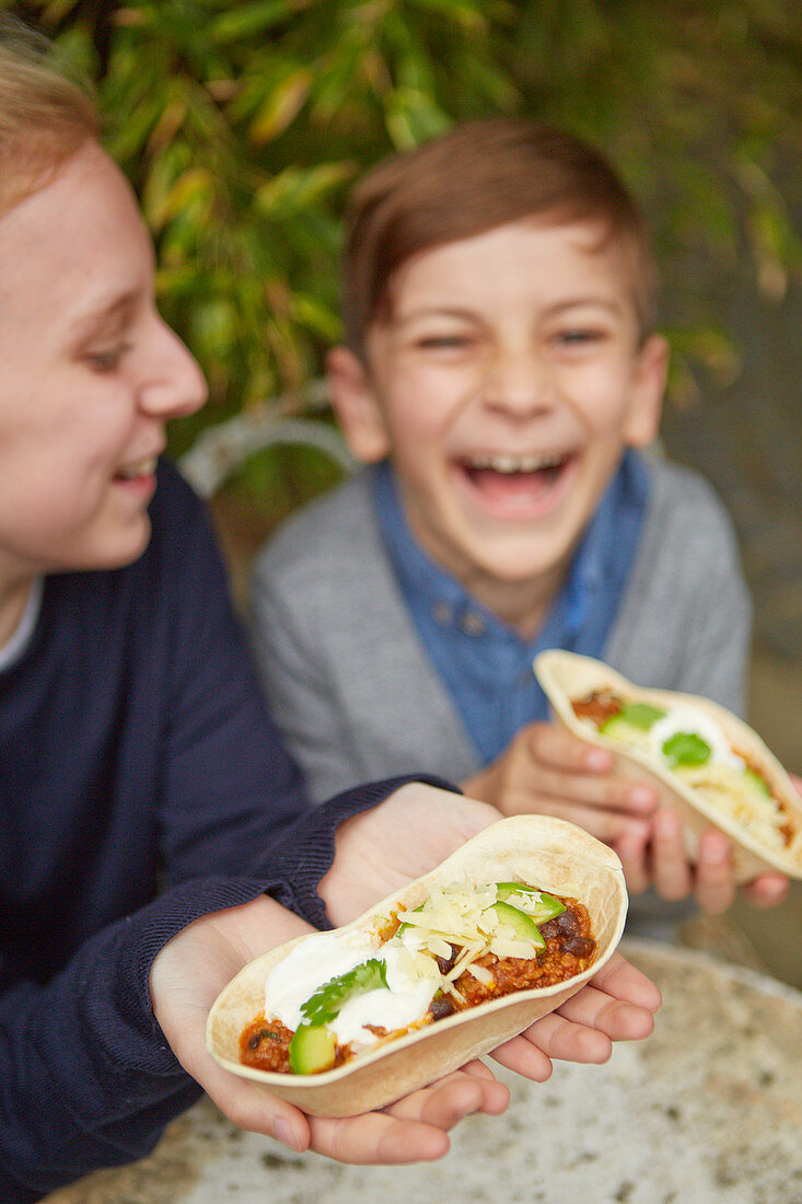 Kids enyoying tortilla bowls with black bean chilli